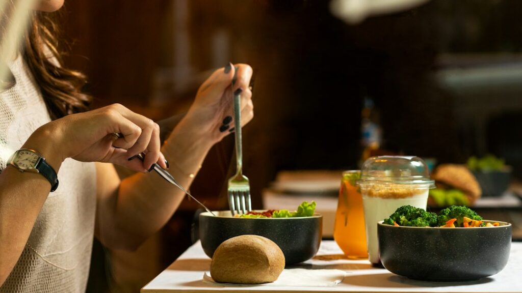 Person eating a colorful home-cooked meal at a table while noticing the food and taking a calm pause.